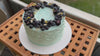 Top view of an artisan gluten free cake decorated with fresh blueberries, blackberries and edible flowers, handmade by Gluten Tag bakery in Copenhagen