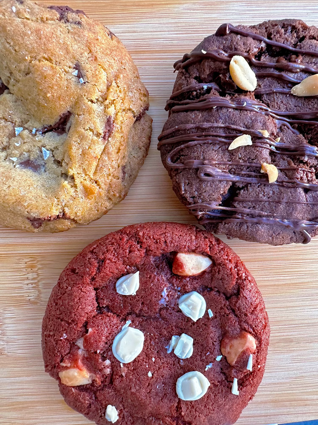 Three vegan gluten-free cookies side by side: red velvet, dark chocolate chip Levain-style, and dark chocolate with peanut butter stuffed, all handmade by Gluten Tag in Copenhagen.